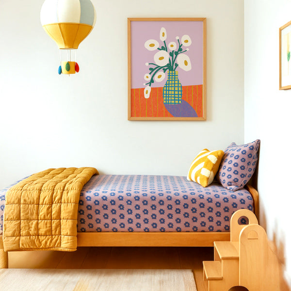 Children's bedroom with a bed, colorful bedding, and colorful floral wall art.