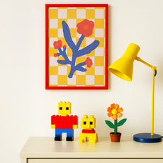 Colorful room decor with a checkered wall art, yellow lamp, and toy figures on a shelf.