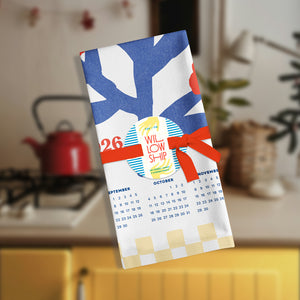 Folded tea towel with checkered border, tied with a simple ribbon for gifting.