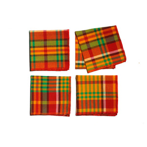Flat-lay of four Merry Madras cocktail napkins arranged in a grid, highlighting the vibrant plaid pattern and festive red serged edges.